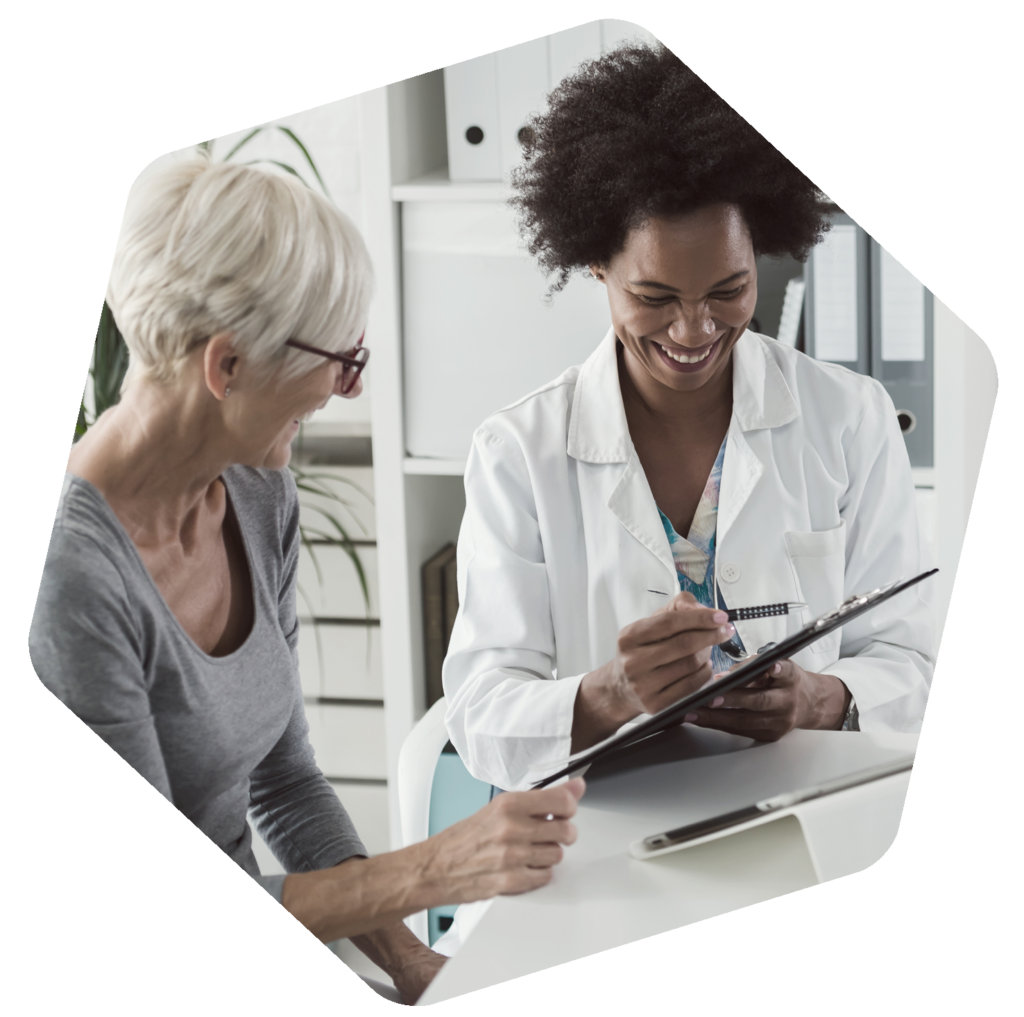 Female healthcare provider pointing to tablet and smiling with older patient.